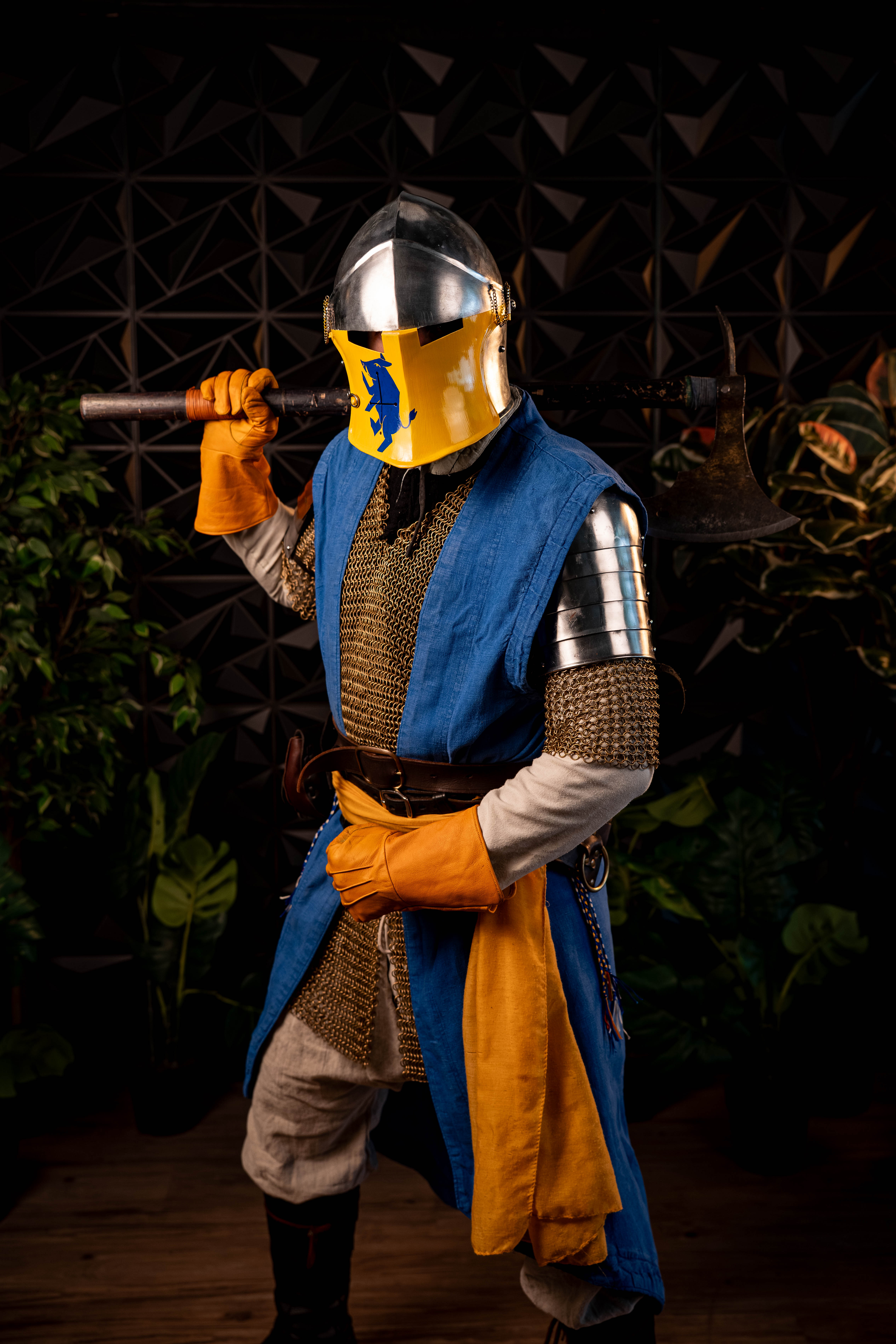 Sebastian Hesse — full body, heraldic helmet, axe over shoulder, plants backdrop